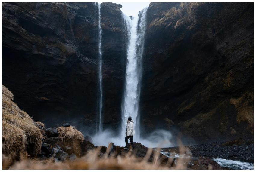A lone traveler stands before the powerful Skógafo