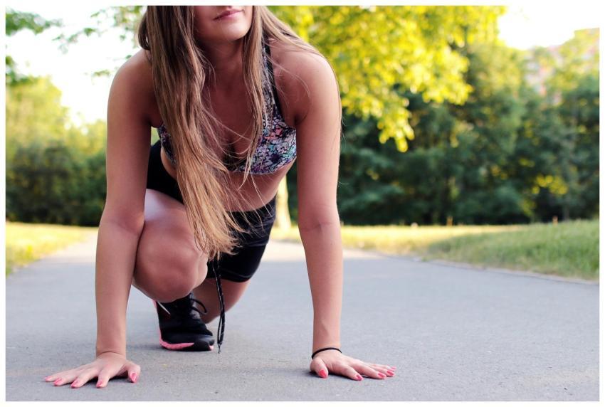 Young woman in athletic wear ready to sprint on a