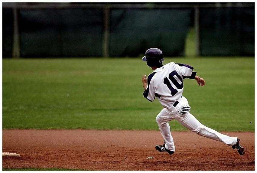 A young baseball player in uniform sprints towards