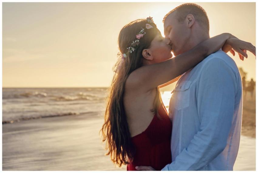 Young couple sharing a romantic kiss on a beach at