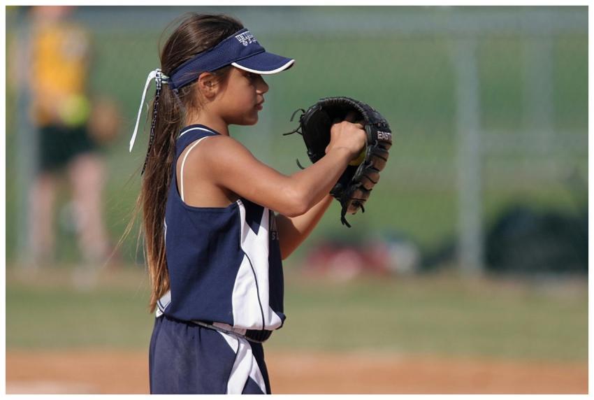 Young girl playing softball, preparing to pitch on