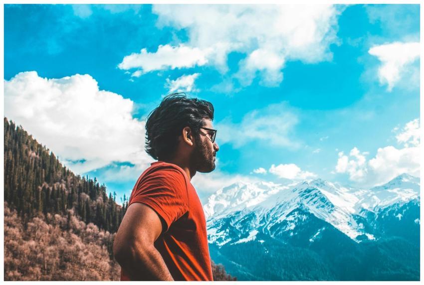 A man in a red shirt stands outdoors, enjoying a s