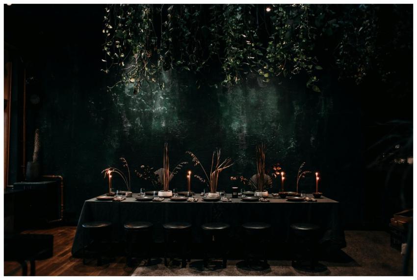 Chic dining setup with candles and hanging plants,
