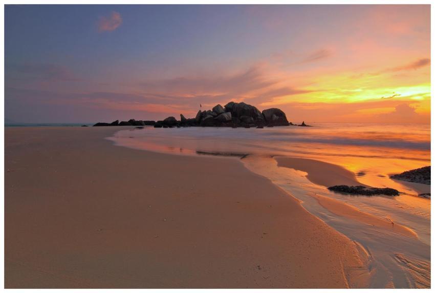 A tranquil beach sunset with vibrant skies reflect