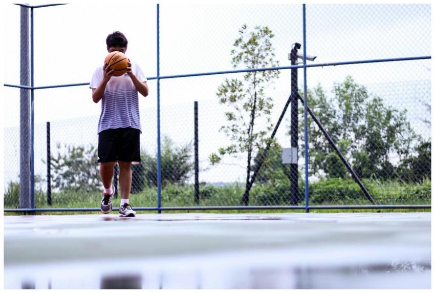 A young man playing basketball on an outdoor court