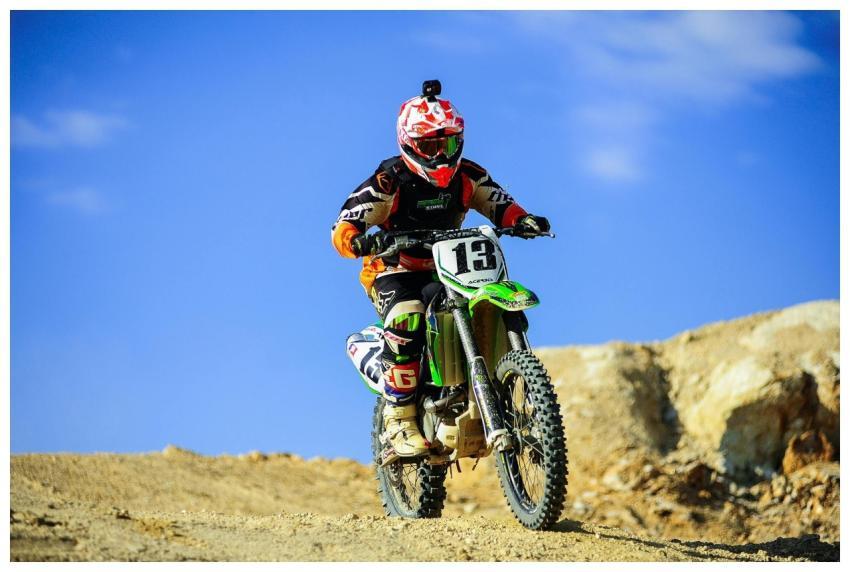 A motocross rider wearing a red helmet and gear ri