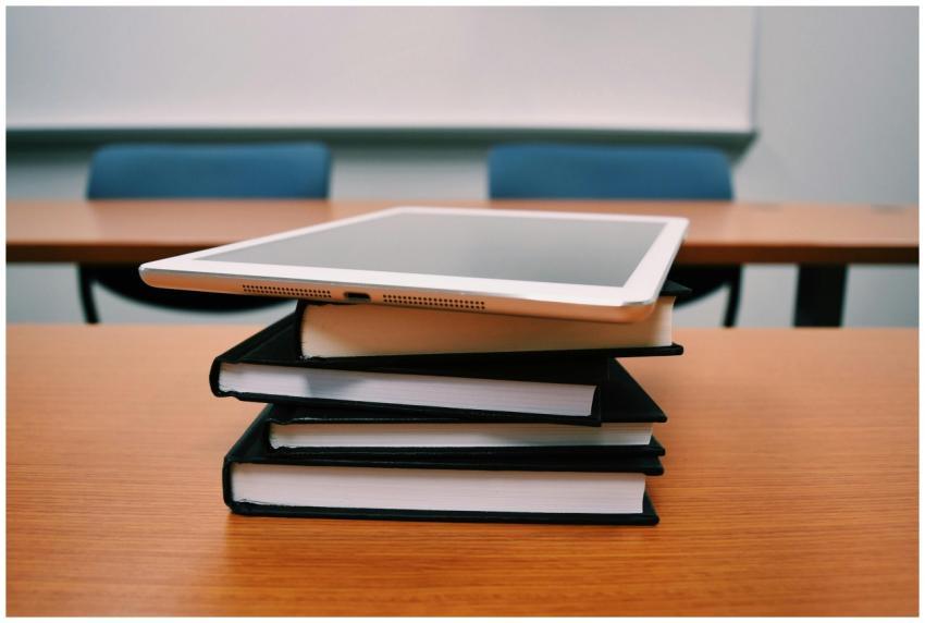 A tablet rests on top of a stack of books in an em