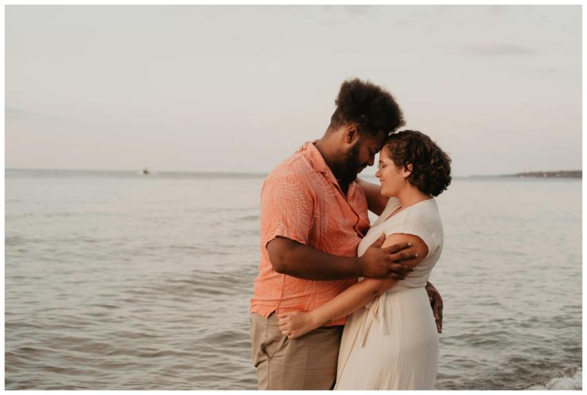A loving couple embraces on the beach at sunset, s