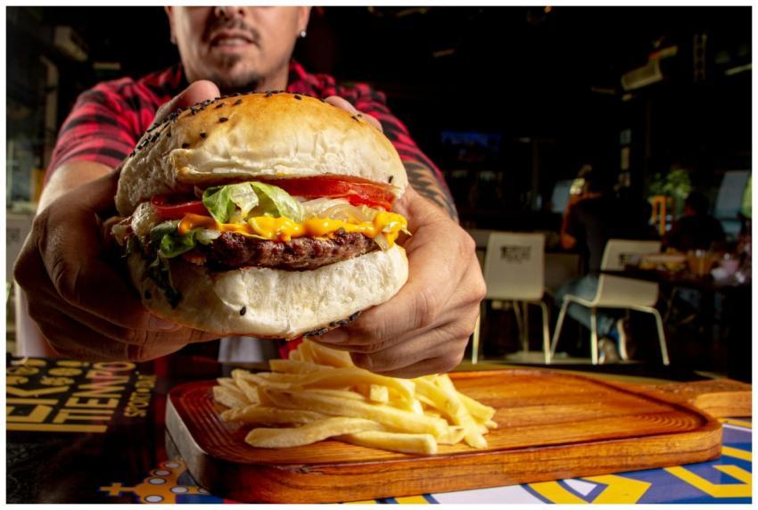 Close-up of a juicy cheeseburger with fries, held