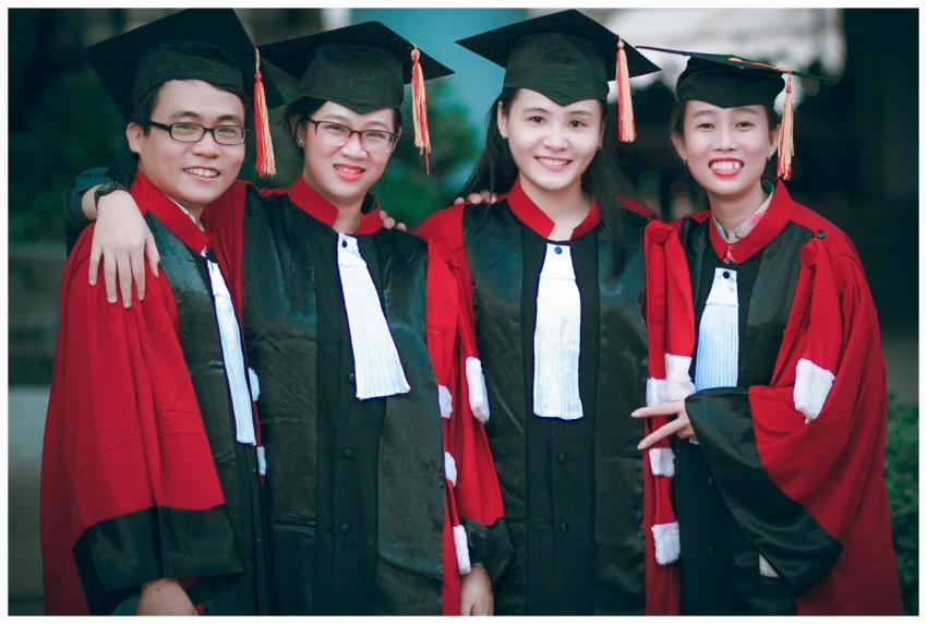 Group of happy graduates in red and black gowns ce