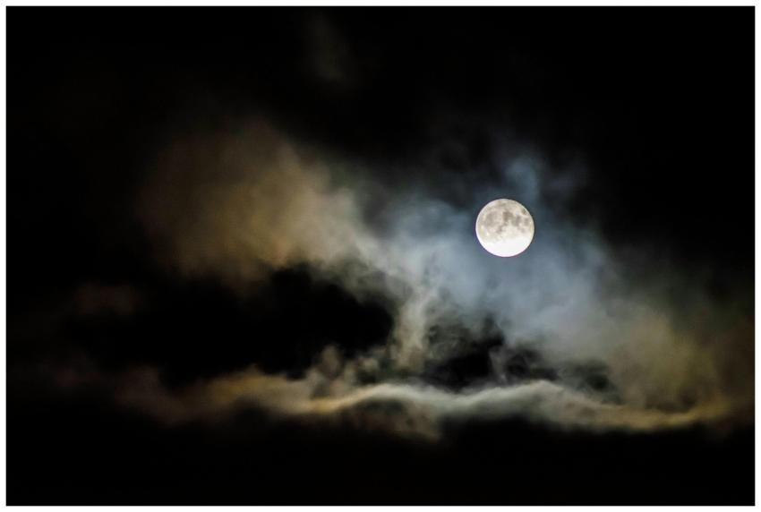 A full moon illuminates the night sky, shrouded by