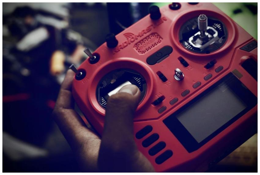 A person operating a red remote control for a dron