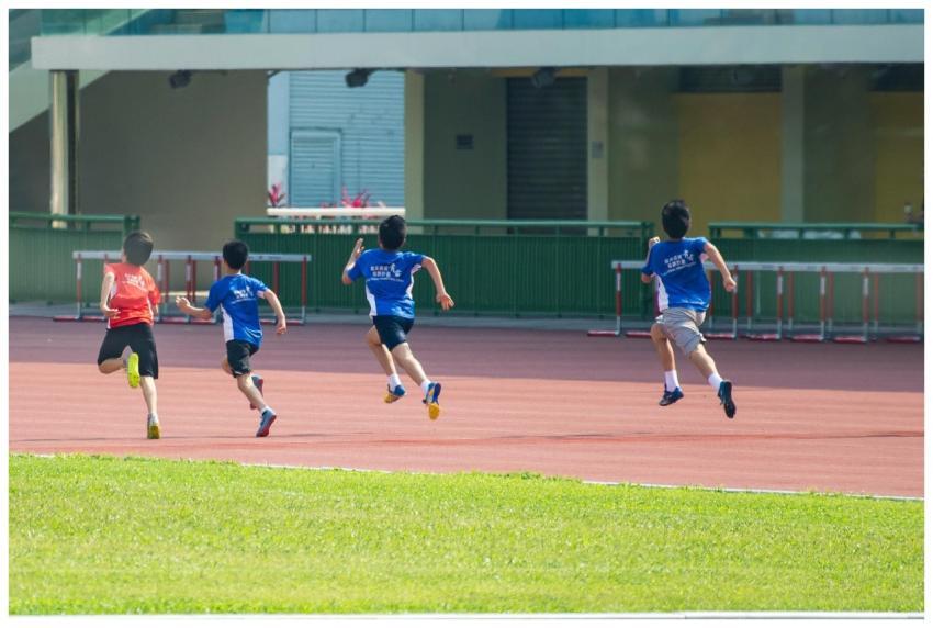 Boys running on a track during a sunny day in New