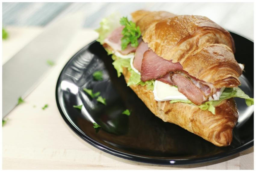 Tasty croissant sandwich with ham, cheese, and veg