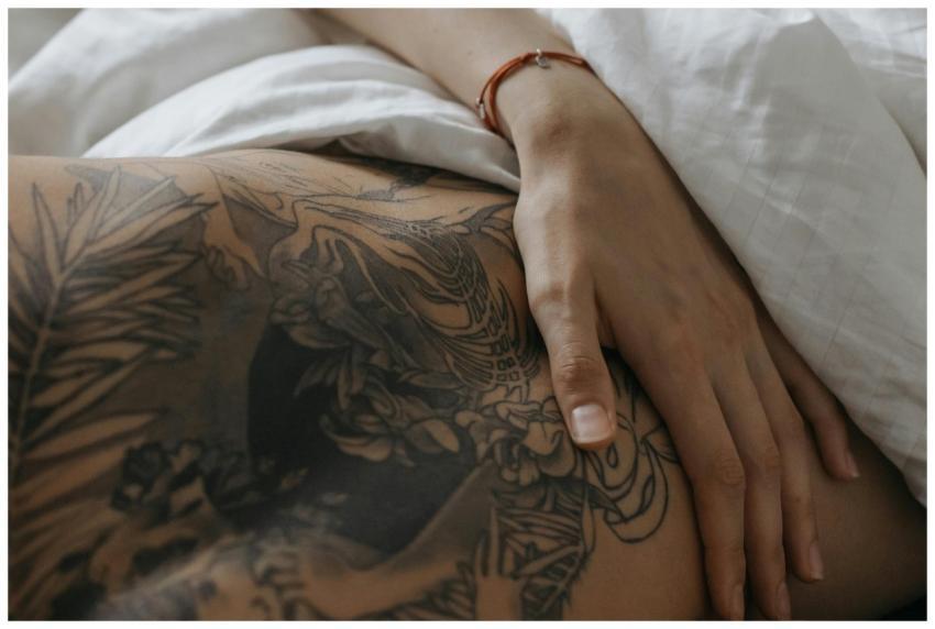 Close-up of a hand resting on tattooed skin, depic