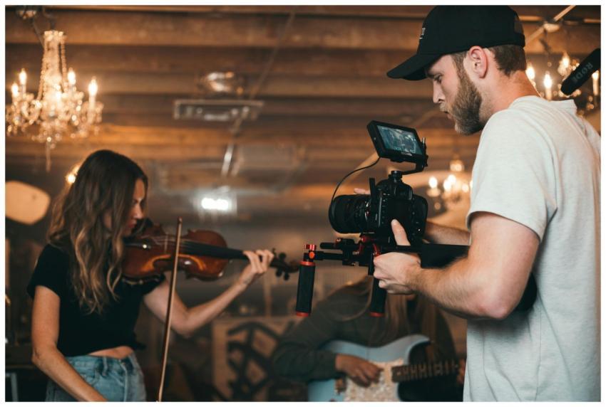 A filmmaker capturing a violinist on set, highligh