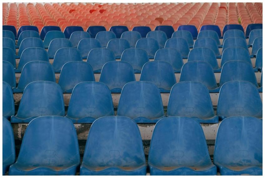 Rows of empty blue plastic seats in an outdoor sta