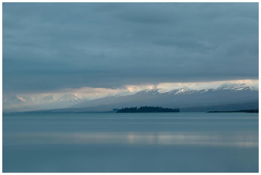Peaceful lake with snow-covered mountains and clou