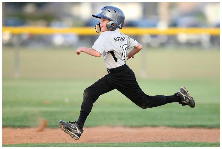 Action shot of a young baseball player running fas