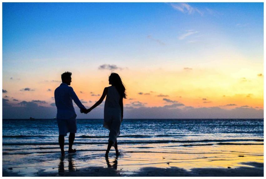 A romantic couple walks hand in hand on a tropical