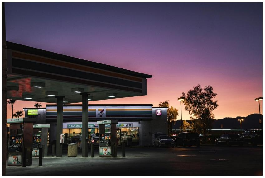 A gas station at dusk with a vibrant sunset backgr