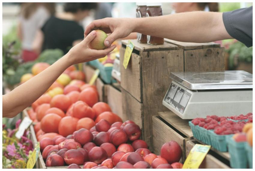 A customer exchanges an apple with a vendor at a v