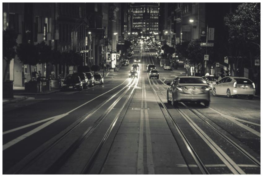 Black and white photo of cars driving on a city st