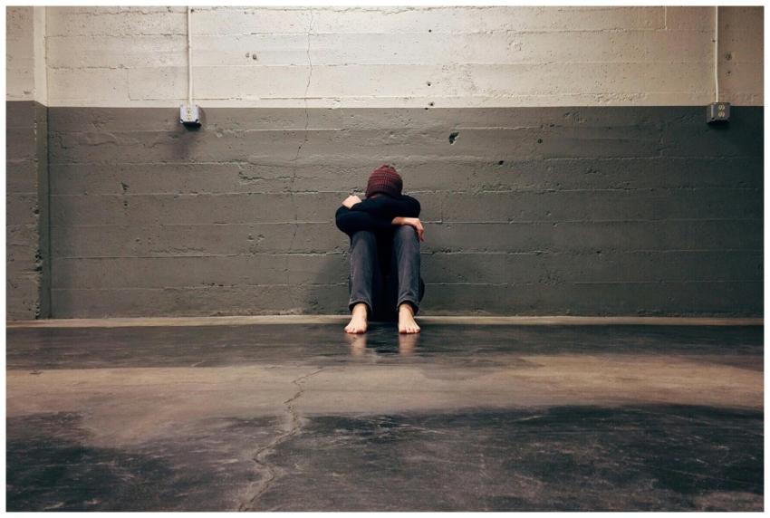 A person sitting alone in a corner, evoking themes
