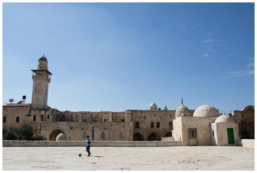 A young boy kicking a ball in front of an ancient