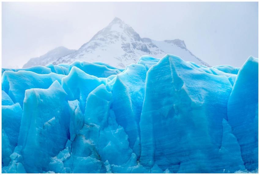 A stunning view of a vibrant blue glacier set agai