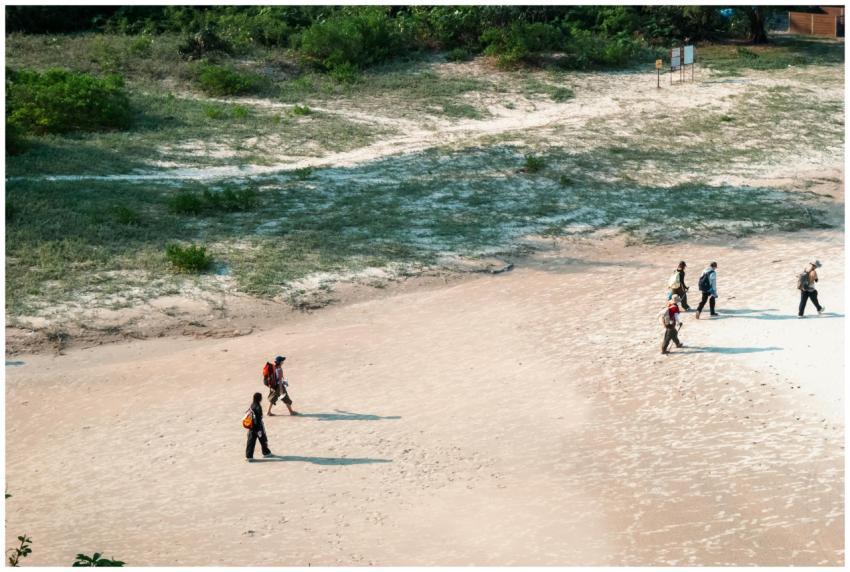 Aerial view of multiple hikers walking on a sandy