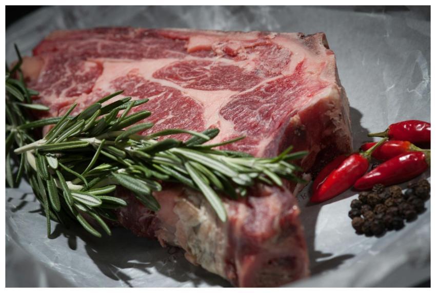 Close-up of a raw steak garnished with rosemary an