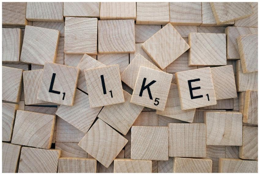 Top-down view of Scrabble tiles spelling 'LIKE' on