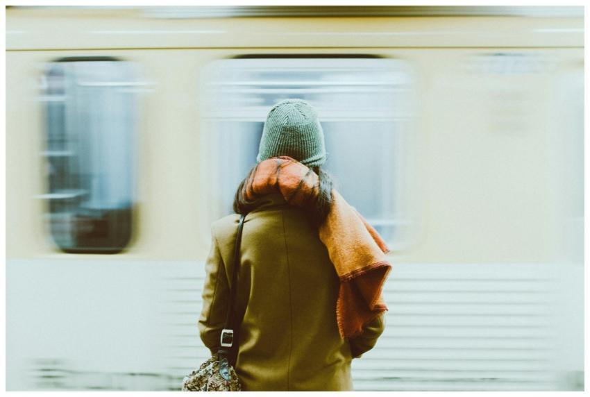 A woman in winter attire waits for a train at a Ne