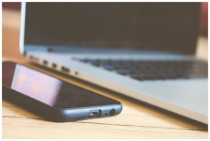 Close-up view of a smartphone and laptop on a wood