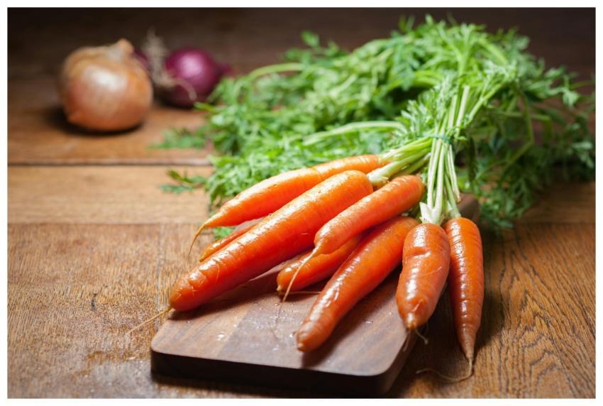 A bunch of fresh organic carrots on a wooden board