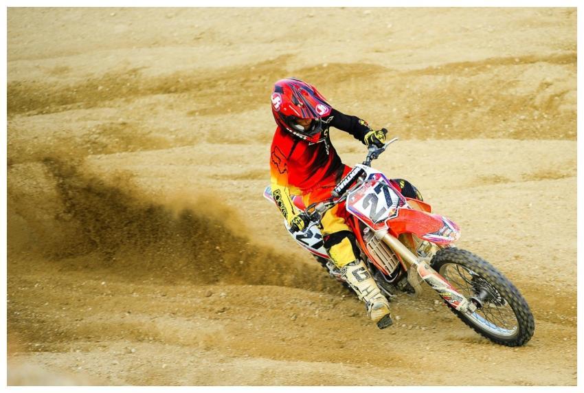 Motocross rider carving through the dirt track wit