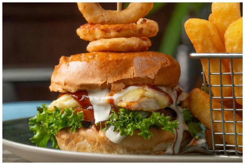 Close-up of a chicken burger with onion rings and