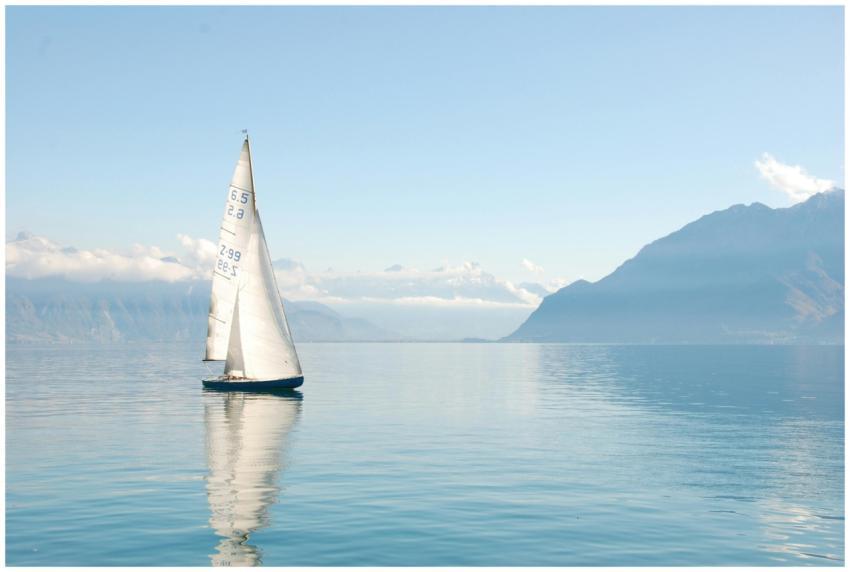 Sailing boat glides peacefully on a misty lake sur