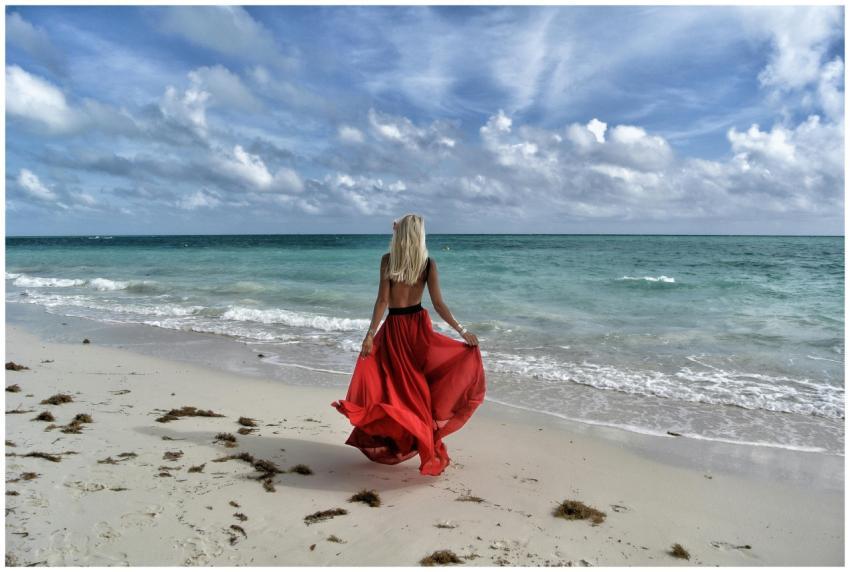 A woman in a flowing red dress enjoys a walk on a