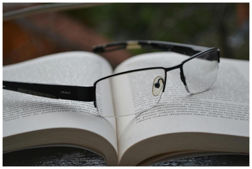 Eyeglasses resting on an open book, symbolizing kn