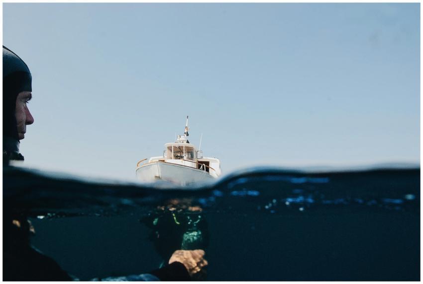 A diver underwater with a yacht on the surface, sh