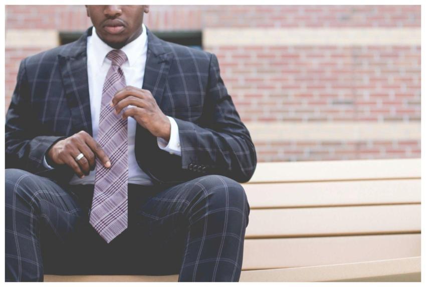 A confident, professional man adjusts his tie whil