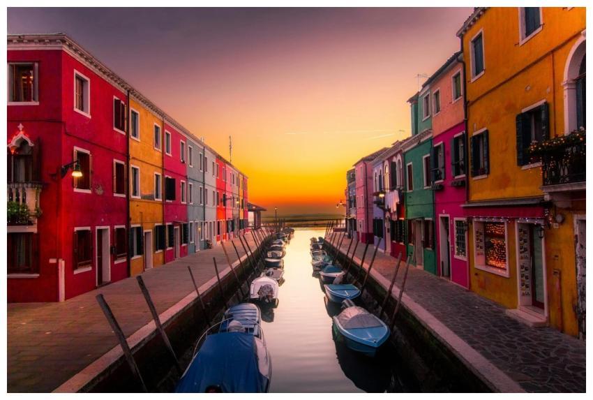 Vibrant facades along Burano's canal with boats at
