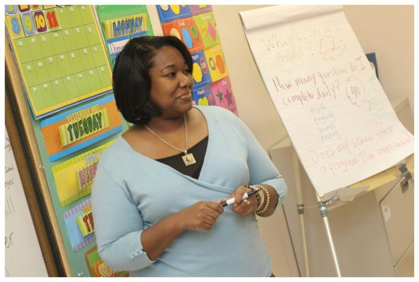 A female teacher standing by a whiteboard in a col
