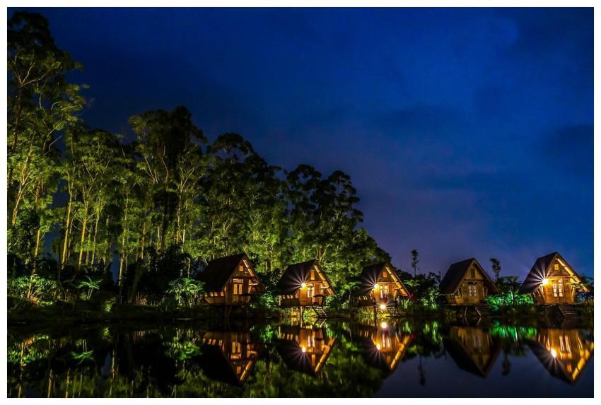 Stunning lakeside huts reflect in water under a ni