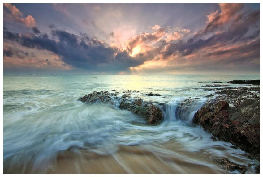 Beautiful sunrise over ocean rocks with waves cras