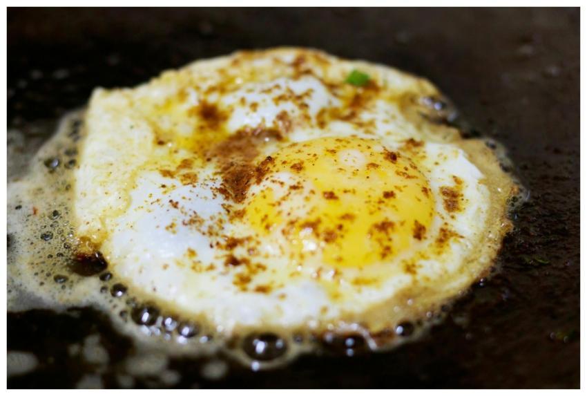 Mouthwatering fried egg with crisp edges cooking o