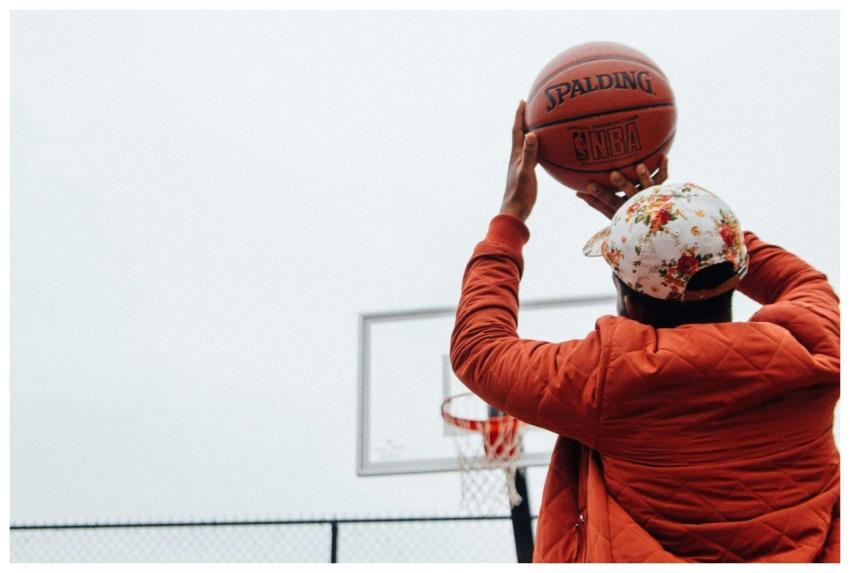 Back view of a man shooting a basketball on an out
