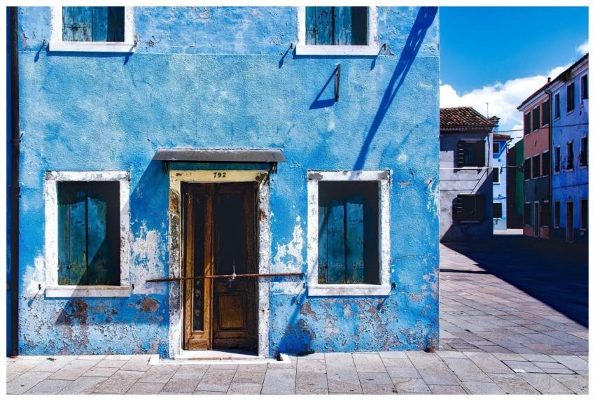 An old, rustic blue building with wooden windows c